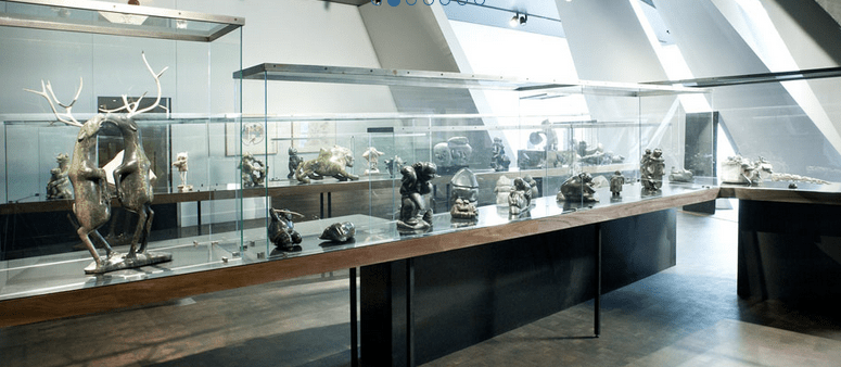 The Inuit Art collection at the Montréal Museum of Fine Arts. Stone sculptures in glass cases; most prominently in the foreground, two caribou on their hind legs, dancing, almost kissing. http://itineraires.musees.qc.ca/en/first-nations-inuit-cultures/museums/montreal-fine-arts