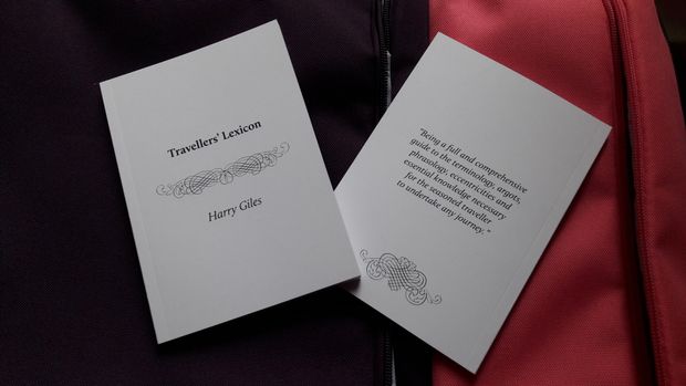 Two small white books lie on a red suitcase; they read "Travellers' Lexicon"